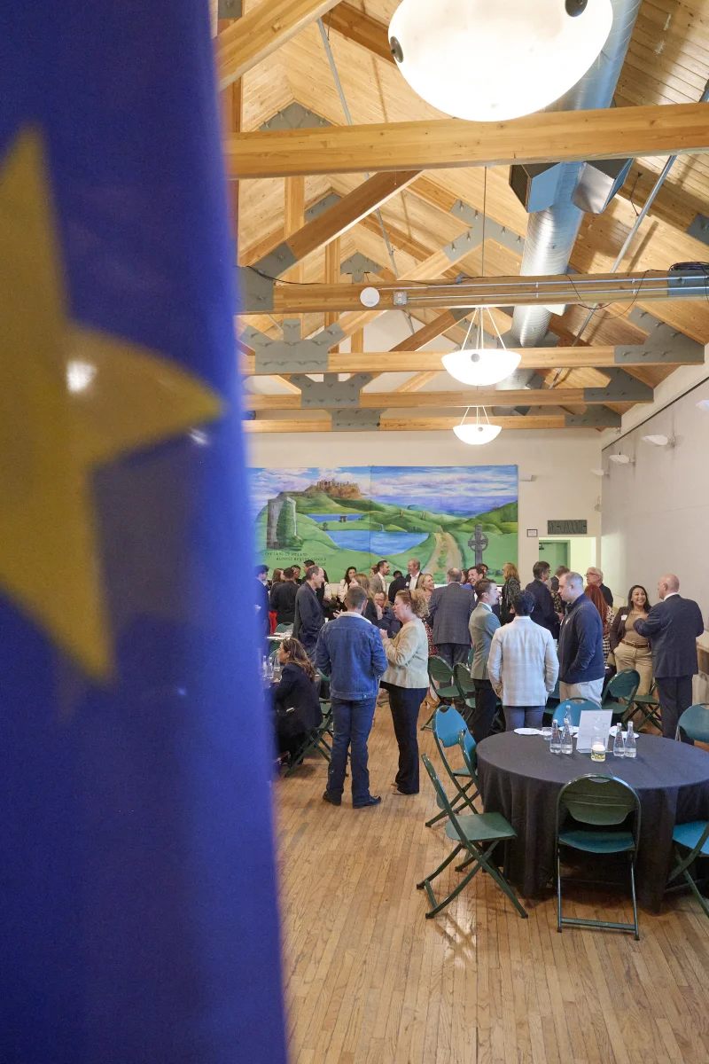 Arizona-European Young Entrepreneur Award ceremony networking reception at Irish Cultural Center Phoenix with EU flag in foreground and business leaders mingling in background