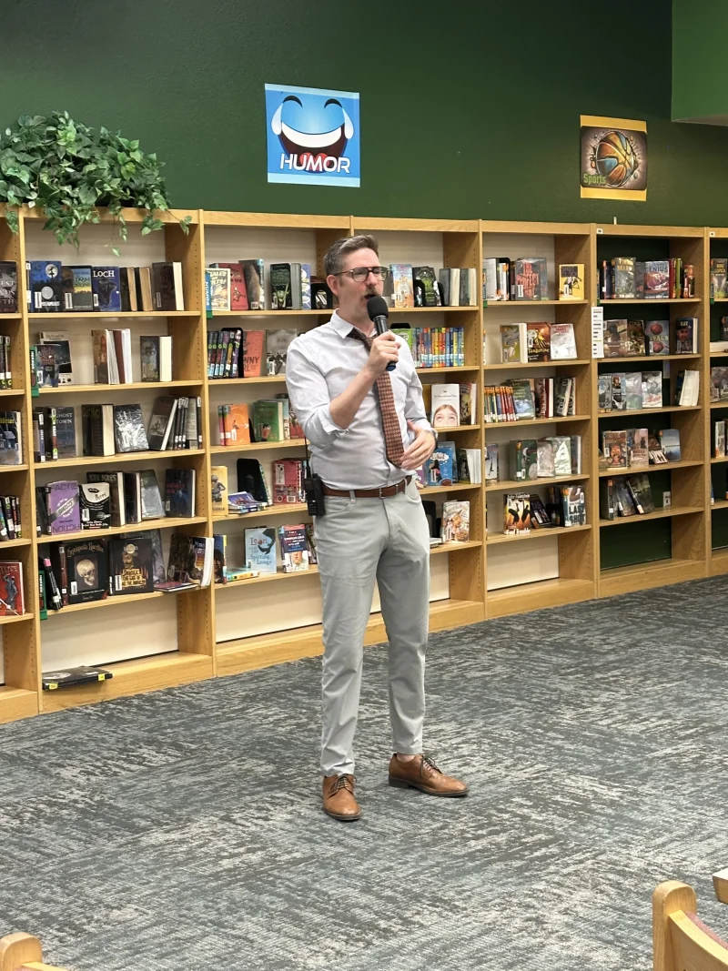 Friend dressed as a plainclothes inspector with white shirt, loosened patterned tie, and visible shoulder holster, demonstrating an intentional rule-breaking look for character headshots