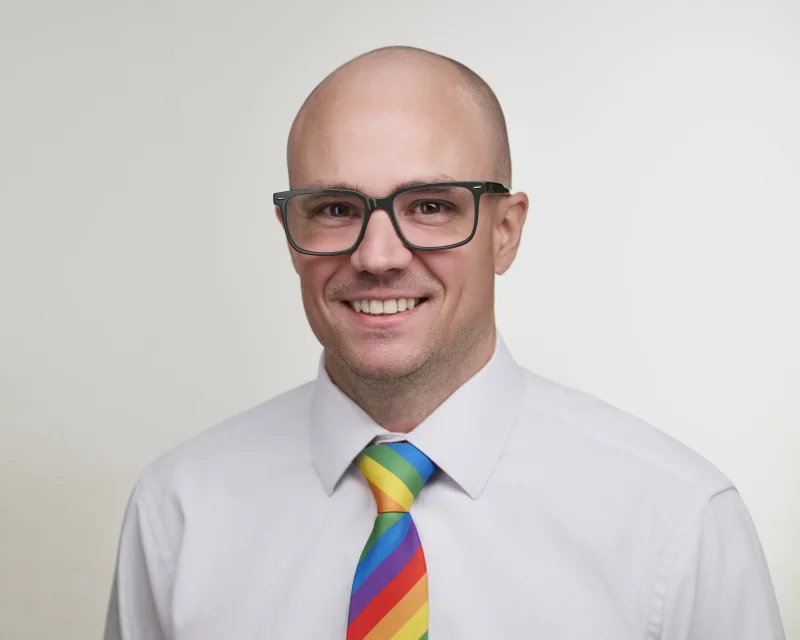 Phoenix professional wearing a rainbow tie with a white shirt and no jacket, a deliberate identity-led headshot statement photographed in Gilbert Arizona