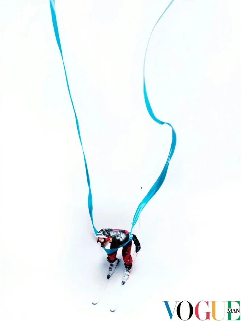 Aerial photograph of a skier descending through white space trailing a flowing blue ribbon, from Team China's 2026 Winter Olympics uniform editorial by Win Tam for Vogue China