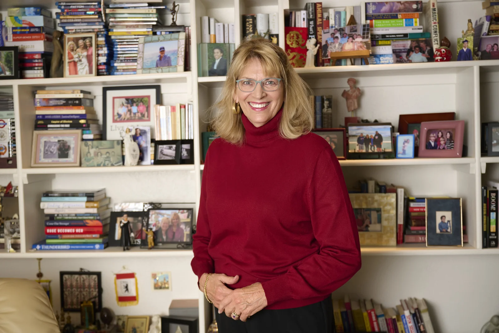Karen Walch photographed on location in her home office, standing in front of shelves of books and framed family photographs, personal branding session by Marie Feutrier in Phoenix Arizona