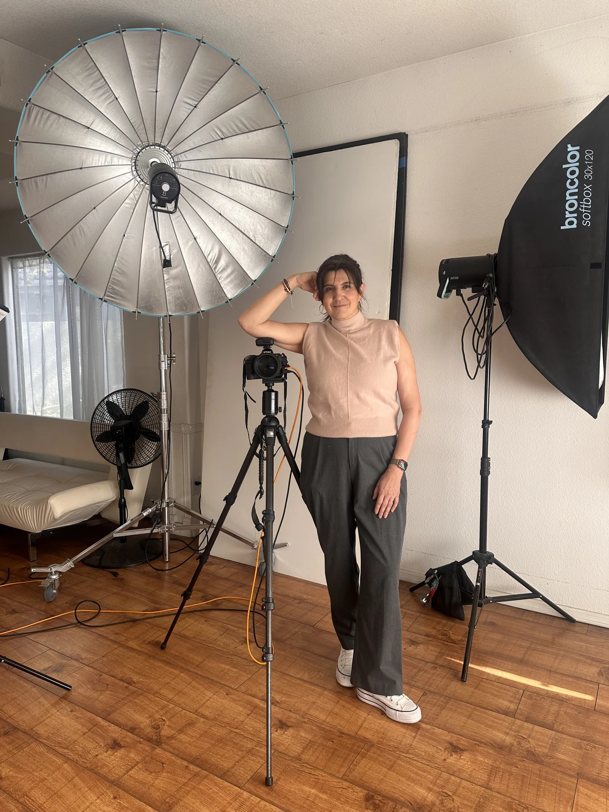 Marie Feutrier in her Gilbert studio, standing beside a camera on a tripod between a Broncolor parabolic reflector and softbox, set up for a personal branding session