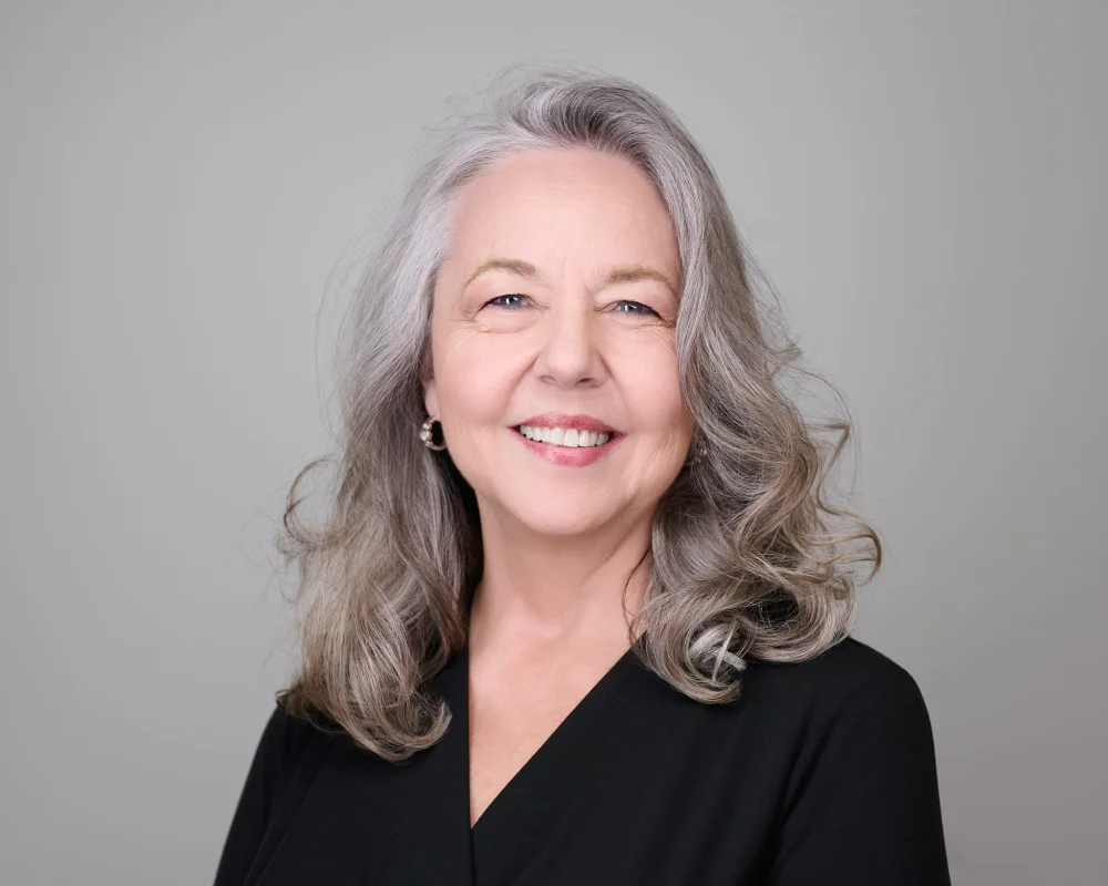 Jan Walsh, natural portrait with silver hair and warm smile against light backdrop by Marie Feutrier