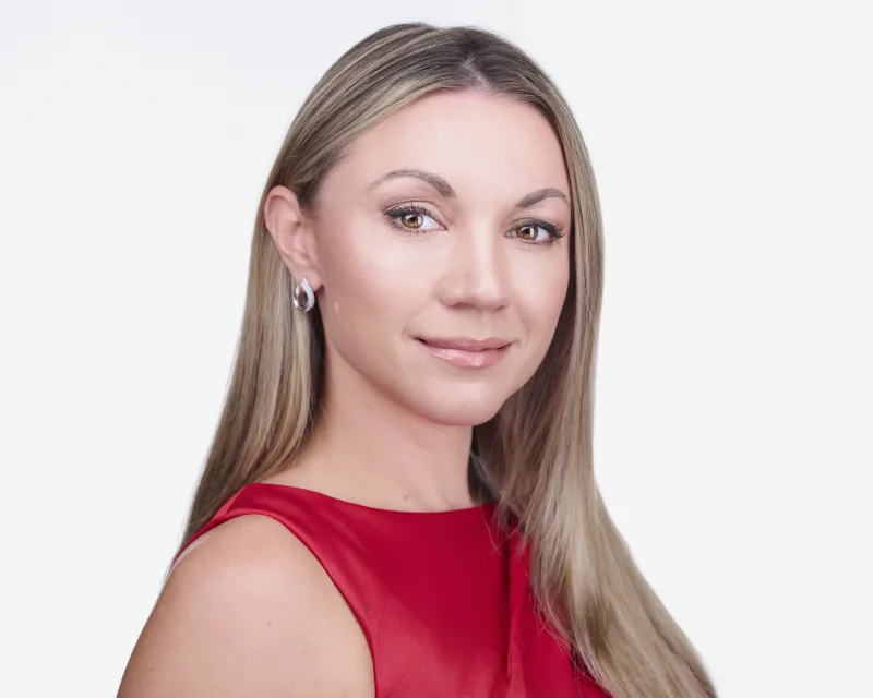 Woman with blonde hair in red sleeveless top and silver hoop earrings polished corporate headshot against white backdrop Phoenix Arizona
