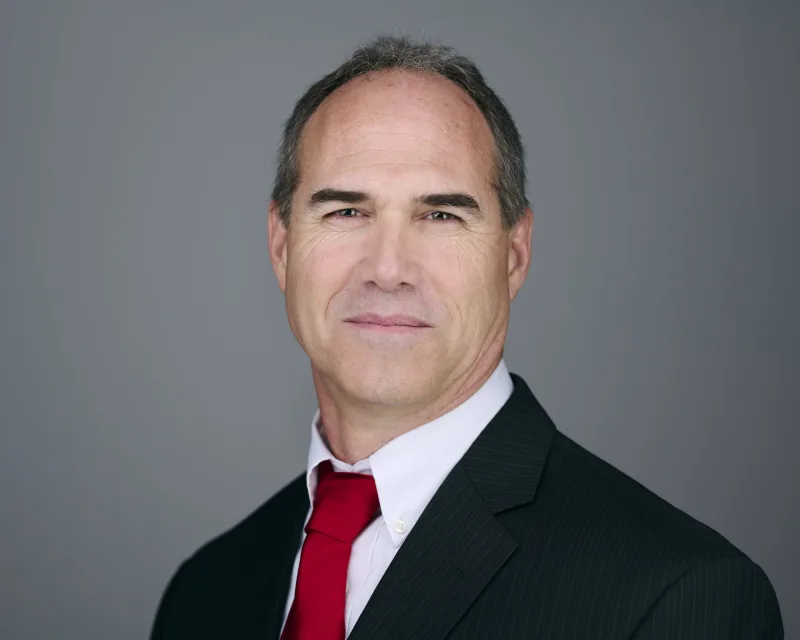 Senior executive in dark pinstripe suit with red tie confident business portrait against gray backdrop Phoenix Arizona