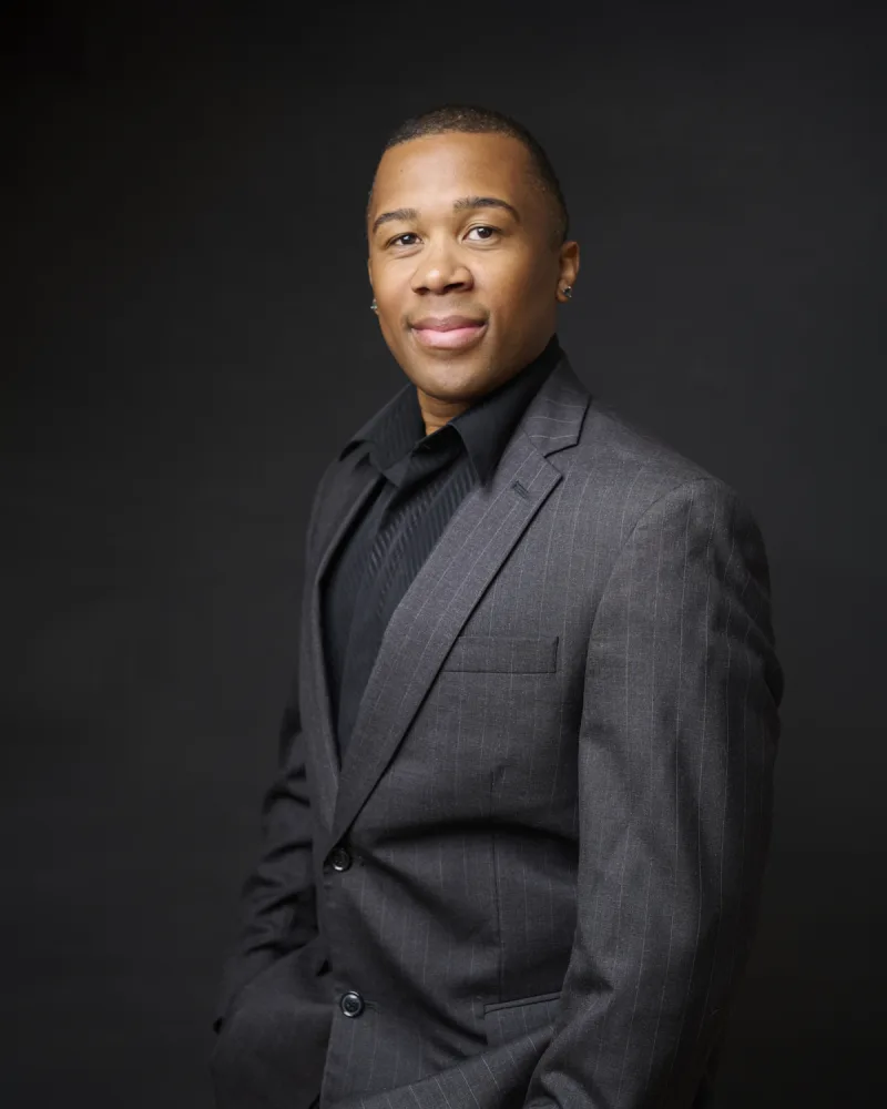 Man in gray pinstripe suit and black dress shirt three-quarter portrait against dark backdrop executive headshot Phoenix Arizona